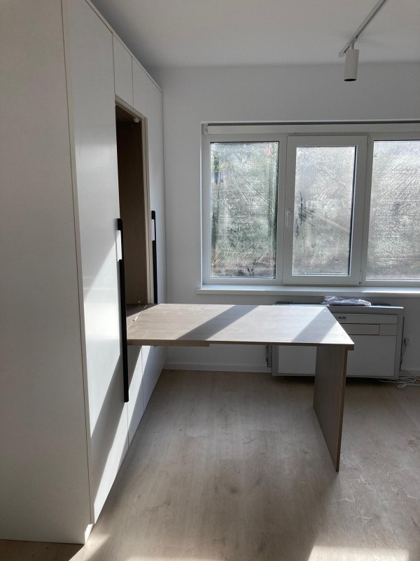 a room with a large window and a white cabinet