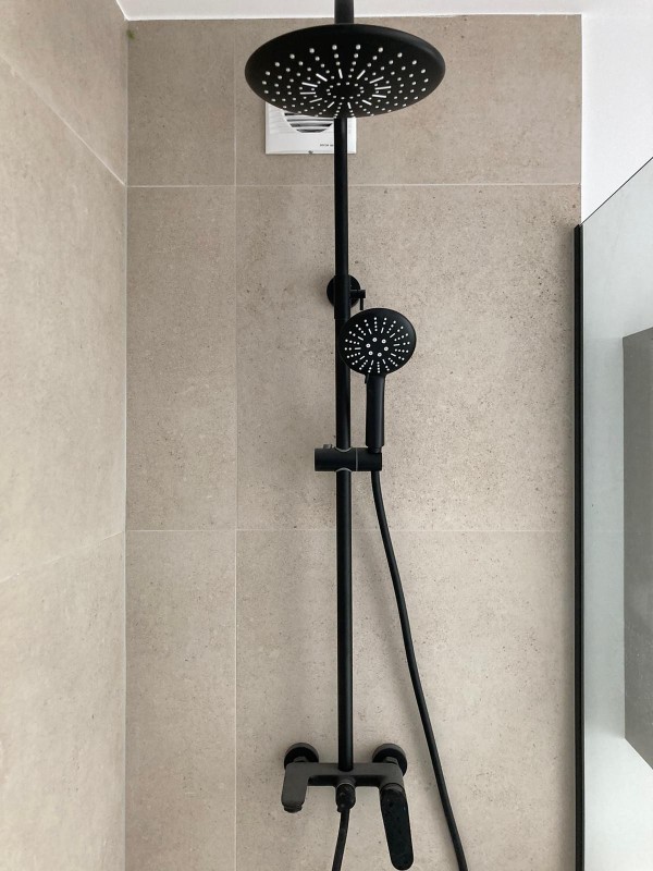 Immerse yourself in luxury with a shower head featuring a black hose and a handheld shower, a symbol of indulgence and grandeur.