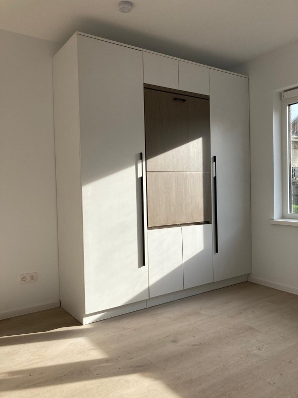 a room with a large window and a white cabinet