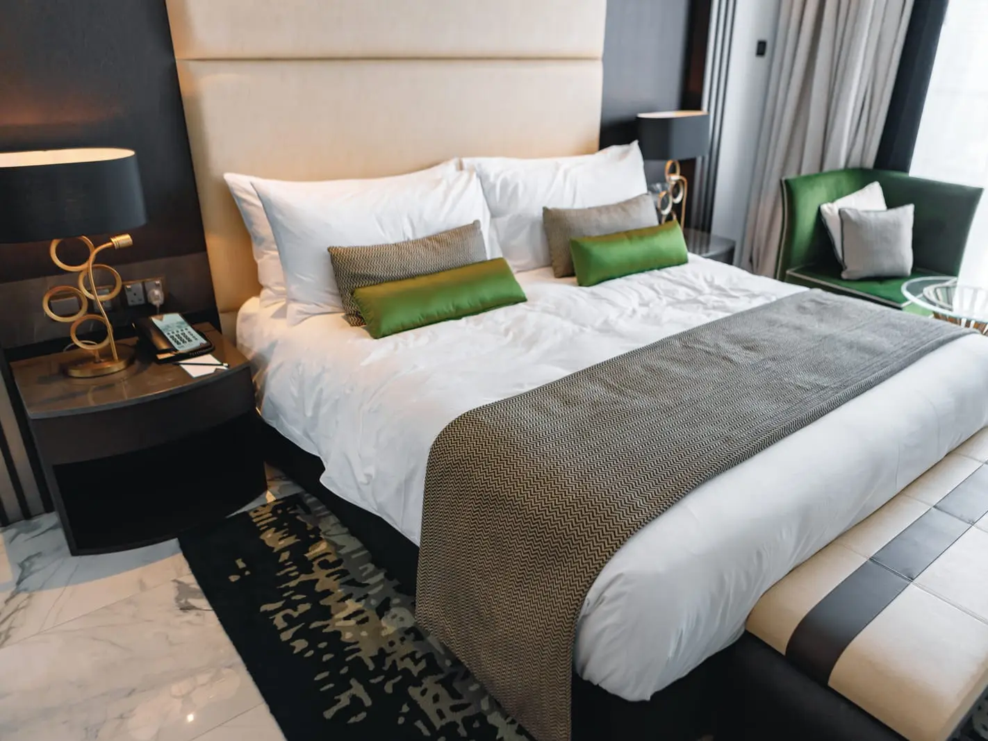 Comfortable hotel room with bed, chair, and green pillows Hotel room with bed, chair, and green pillows