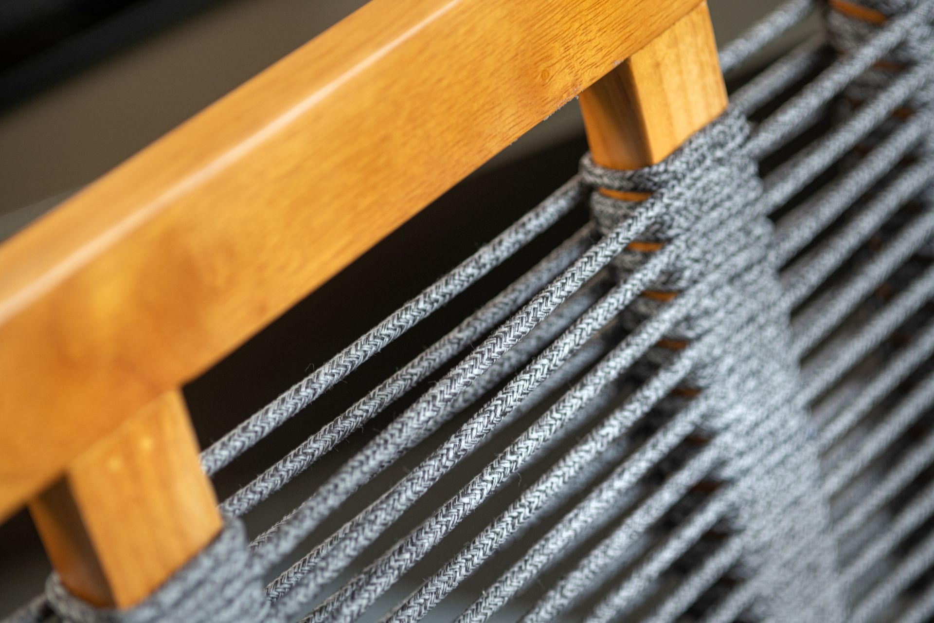A close-up of a wooden chair with a rope. The chair has a rustic charm and the rope adds a touch of uniqueness.