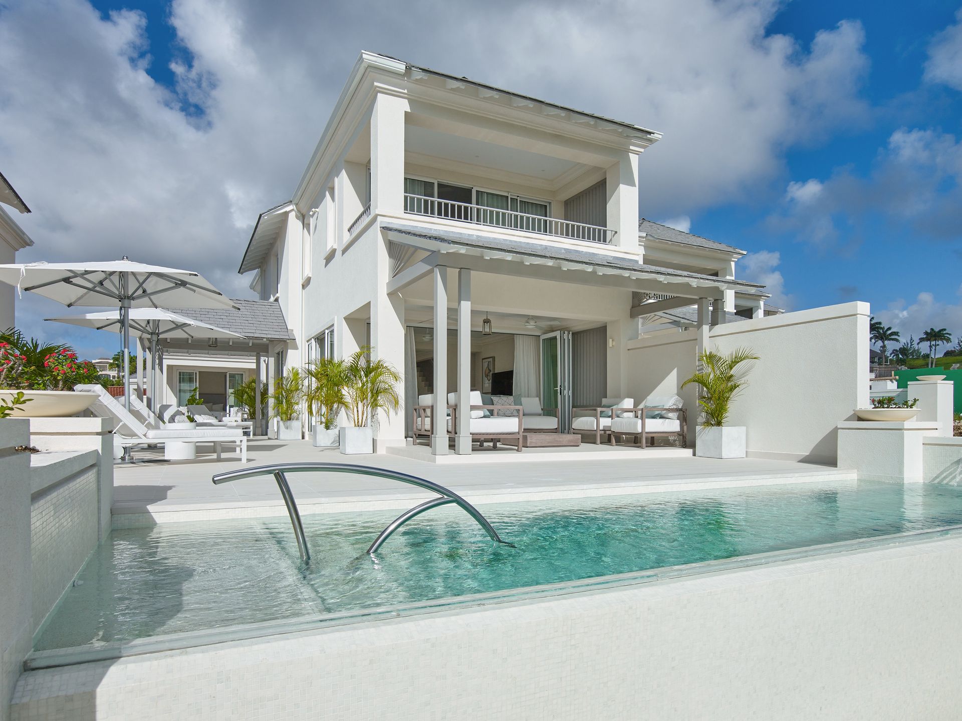 A spacious white house with a pool and patio, perfect for relaxing and entertaining guests.