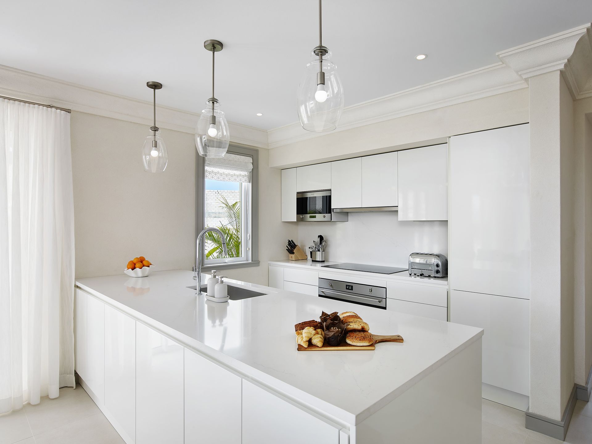 A spacious white kitchen with a large island and a sink, perfect for preparing meals and gathering with loved ones.