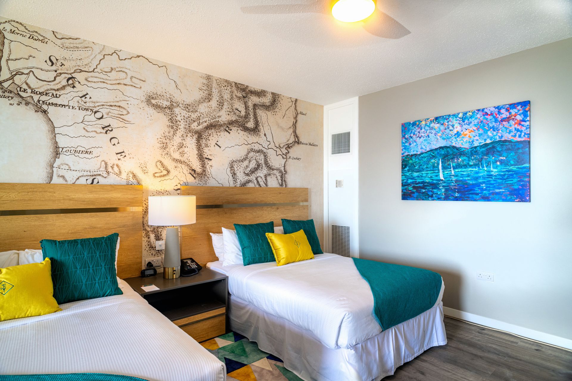 A room with two beds adorned with yellow and green pillows.