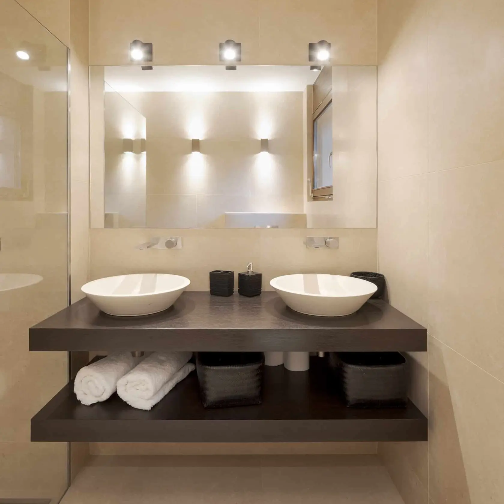 Image of a bathroom with twin sinks and a mirror. A modern bathroom with two sinks and a large mirror, providing convenience and functionality for multiple users.