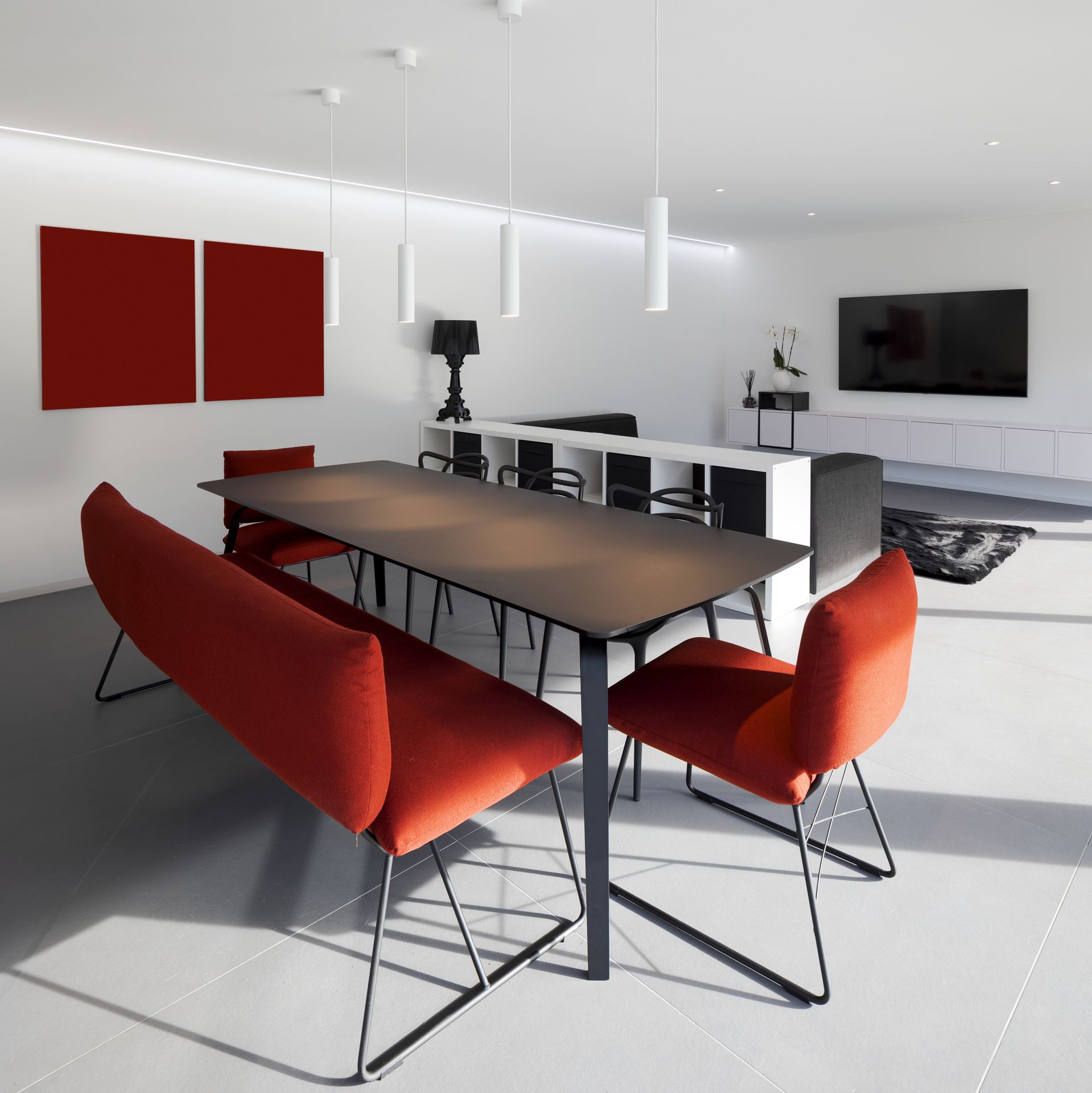 Contemporary dining area with red chairs and black table.