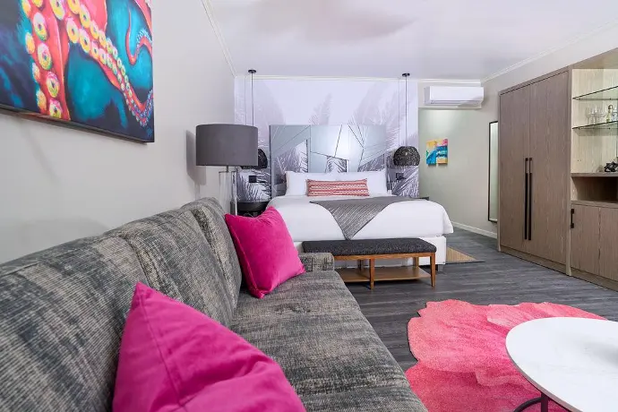Elegant hotel room featuring comfortable bed, stylish couch, and lovely wall painting. Stylish hotel room with inviting bed, chic couch, and captivating wall painting.
